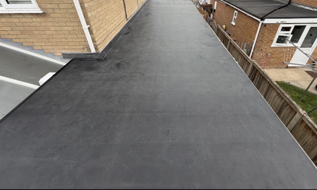 Long residential flat roof covered in smooth dark grey EPDM rubber membrane