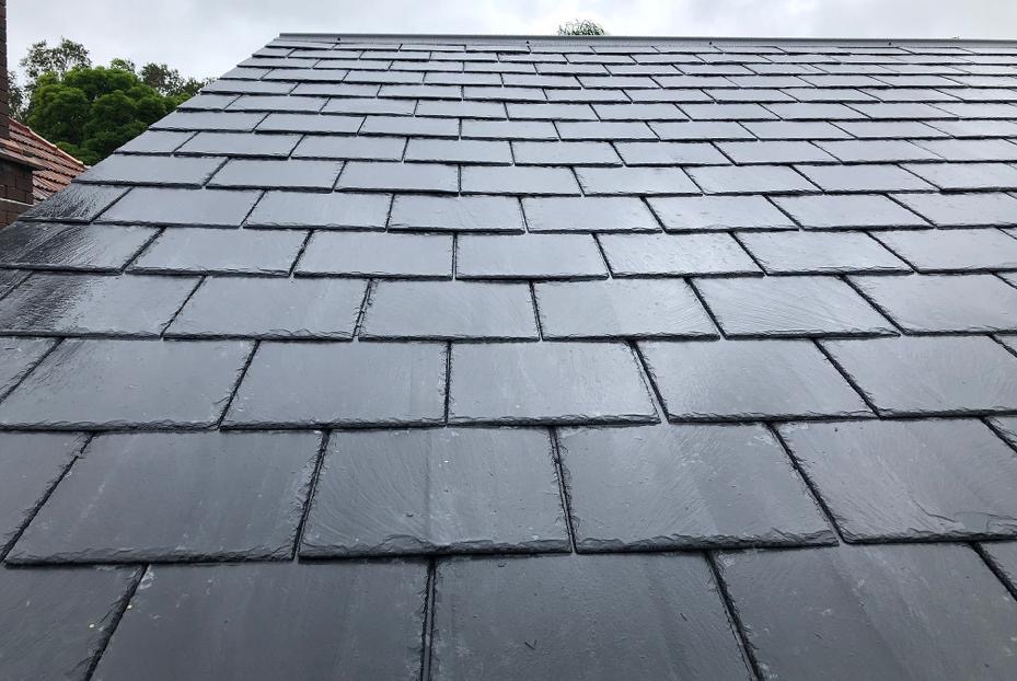 Close-up of a newly finished pitched roof covered in dark grey natural slates