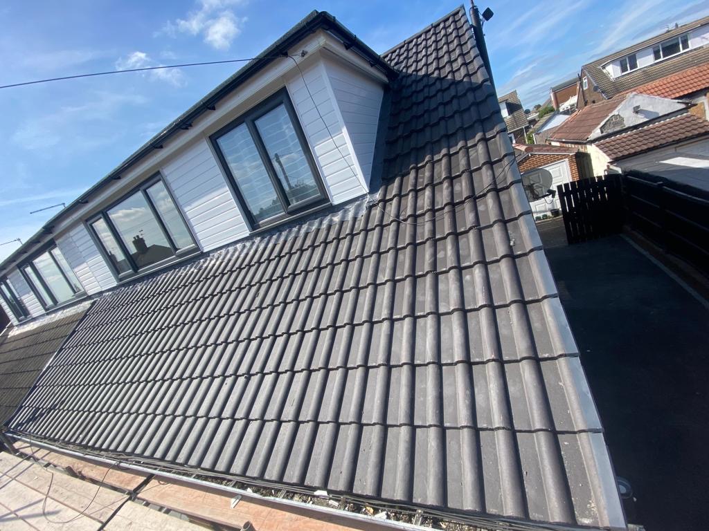Newly tiled roof with dormer under a blue sky