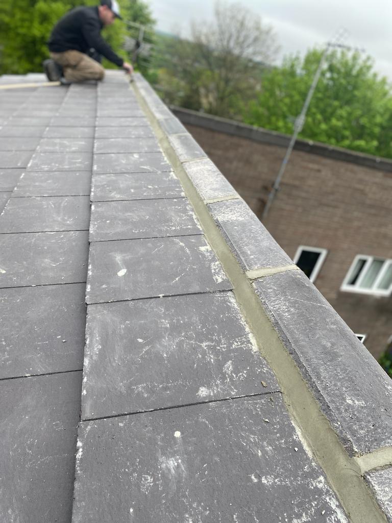 Roofer bedding the ridge tiles on a new roof