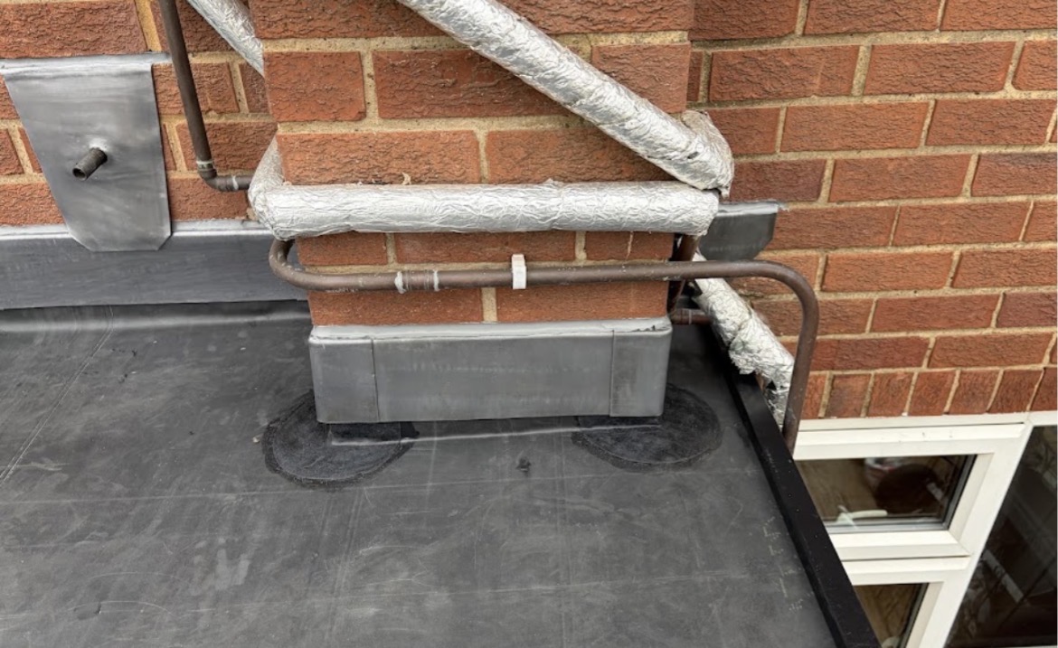 Newly installed lead flashing and black EPDM membrane dressed around a brick pillar on a flat roof